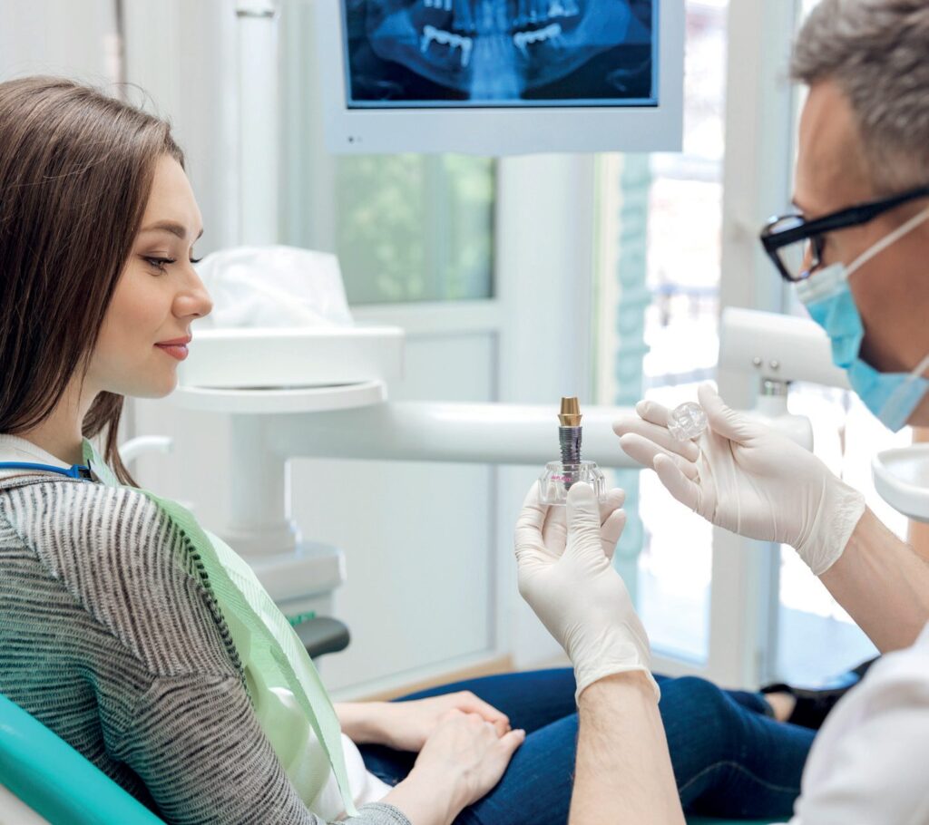 Dentist explaining an implant to a patient in the treatment chair