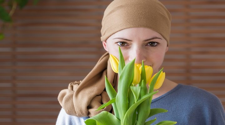 Woman in a headscarf smelling yellow tulips, cancer care theme