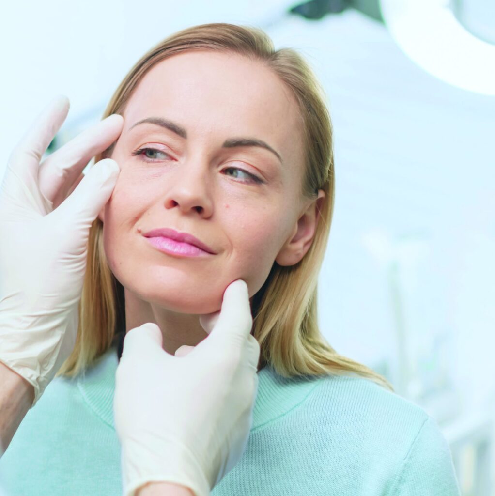 Doctor examining a woman's face during an aesthetic consultation